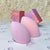 Two pink and lilac Chameleon makeup sponges in different sizes beside their boxes on A’Lei Beauty branded paper.